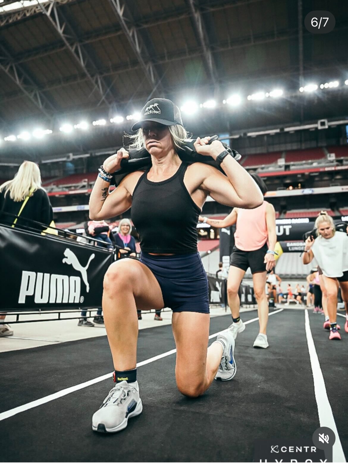 Infinity Fitness AZ coach completing weighted lunges during a HYROX competition